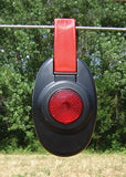 Patriot Red and black electric fence  light-device hanging on a wire with green trees in the background