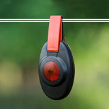 Patriot Black and red clip-on fence alert hanging on a wire with a green blurred background